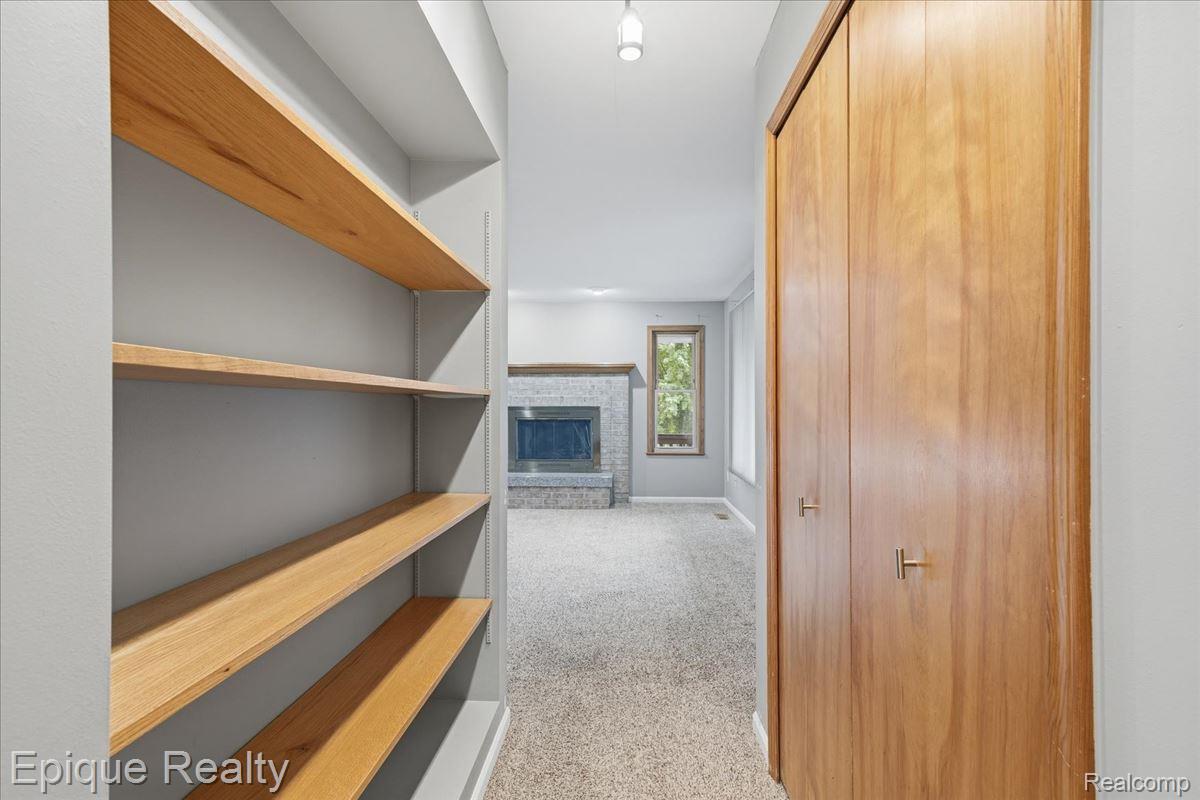 1221 Rhodes Road Lake Orion, MI 48360 - Photo 25 of 72 Hallway featuring built-in wood shelving, natural wood bifold doors with brass hardware, and recessed ceiling lighting