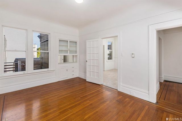 a view of an empty room with wooden floor and a window