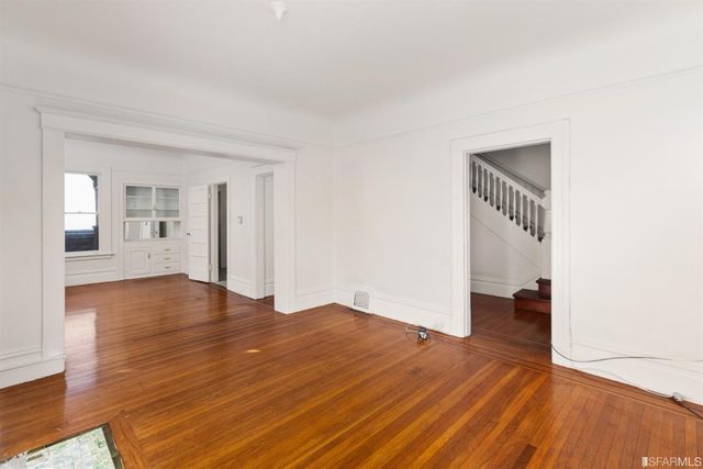 a view of empty room with wooden floor and stairs