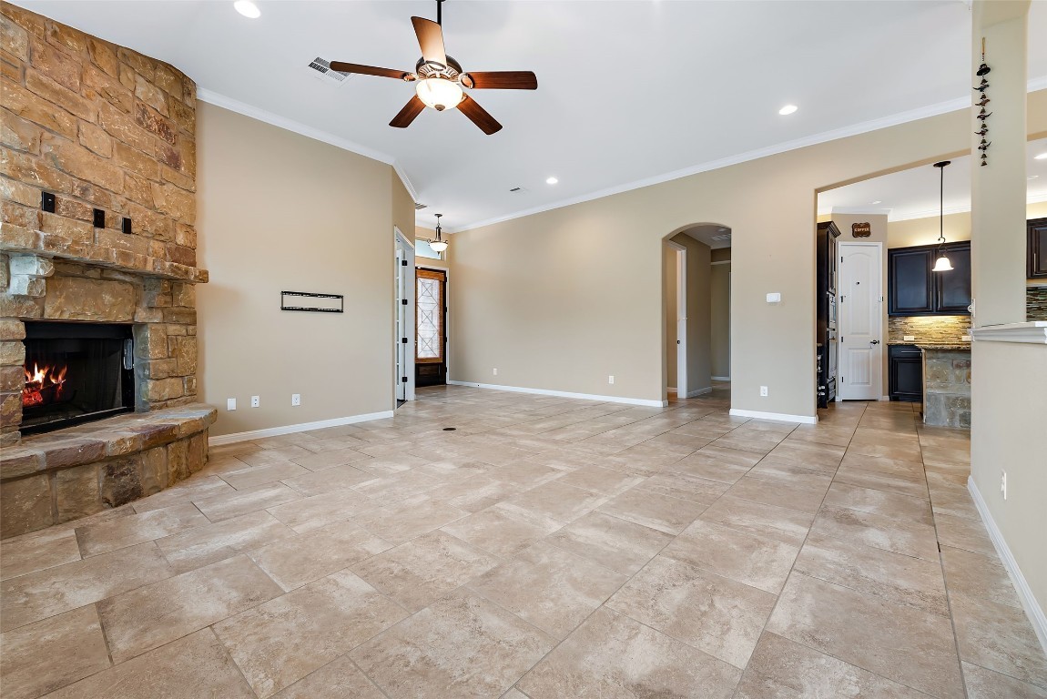 2000 Manada Trail Leander, TX 78641 - Photo 12 of 36 A spacious living area showcasing a rustic stone fireplace and cool tiled flooring.