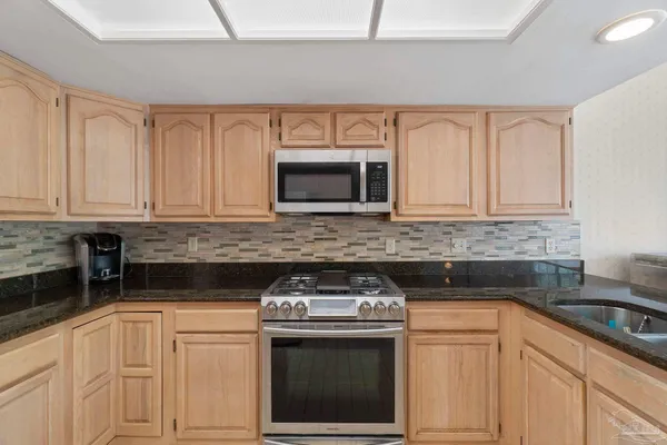 a kitchen with granite countertop a refrigerator and a stove top oven