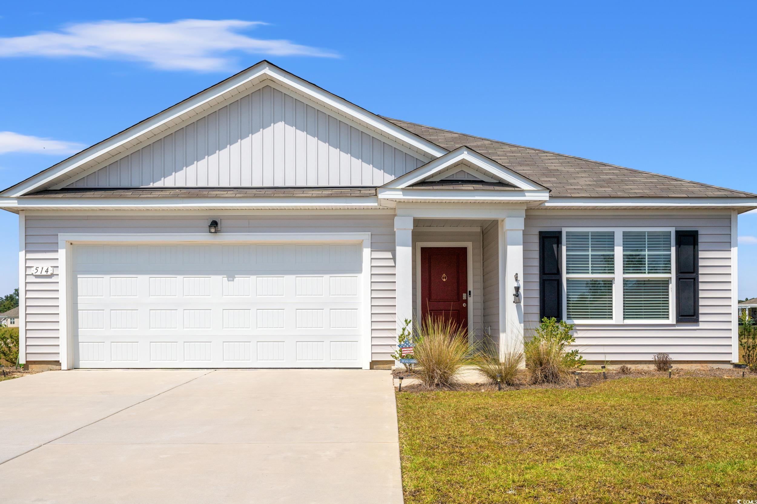 Single story home with roof with shingles, a front yard, a garage, driveway, and board and batten siding