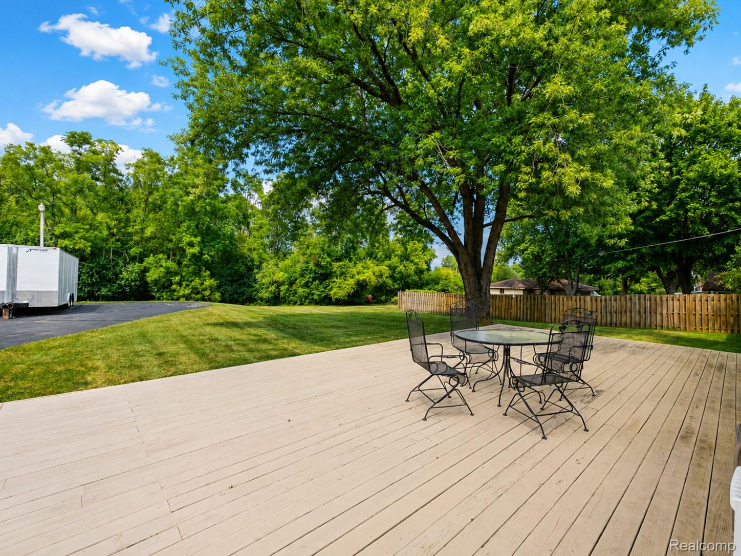 5179 East Baldwin Road Holly, MI 48442 - Photo 27 of 30 Expansive composite deck with mature shade trees and manicured lawn, offering generous outdoor entertaining space