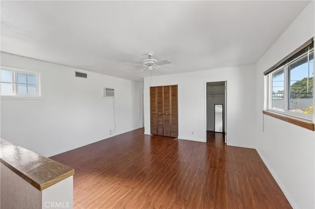 a view of an empty room with wooden floor and a window