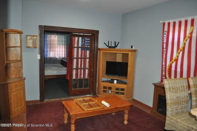 a living room with furniture a flat screen tv and a refrigerator
