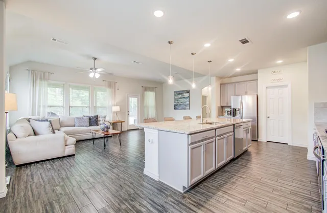 a living room with furniture kitchen view and a wooden floor