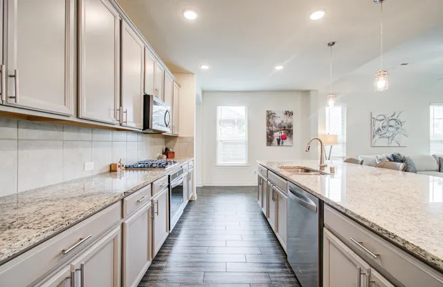 a large kitchen with stainless steel appliances granite countertop a stove and a sink