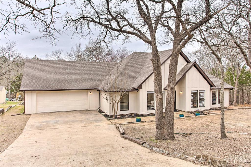 View of front facade featuring concrete driveway, roof with shingles, and an attached garage