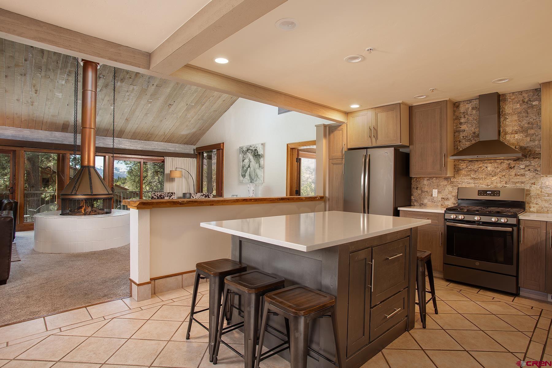 a kitchen with stainless steel appliances granite countertop a table chairs sink and stove top oven