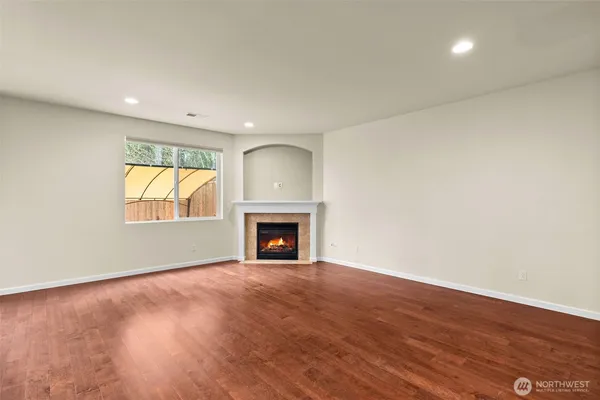 an empty room with wooden floor fireplace and windows