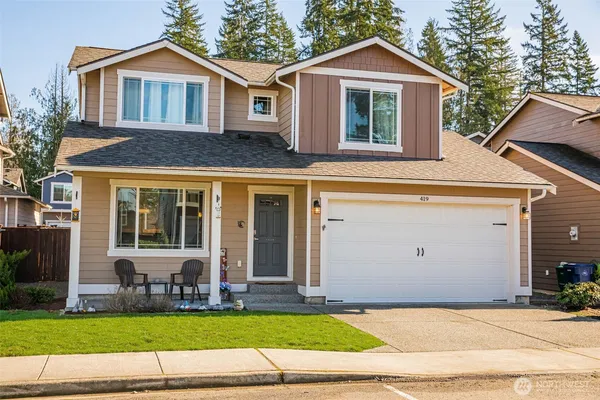 a view of a white house with a small yard and large trees