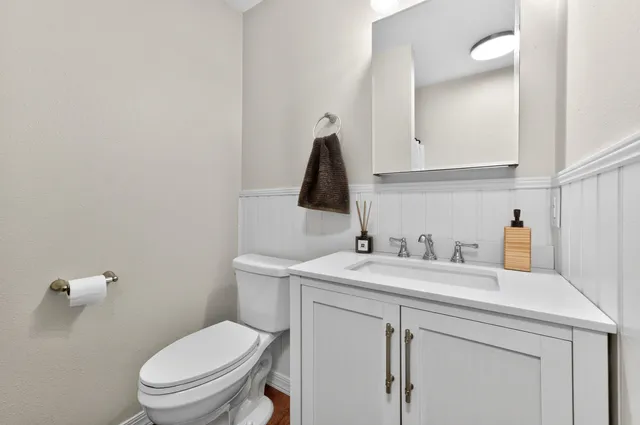 a bathroom with a granite countertop toilet sink and mirror