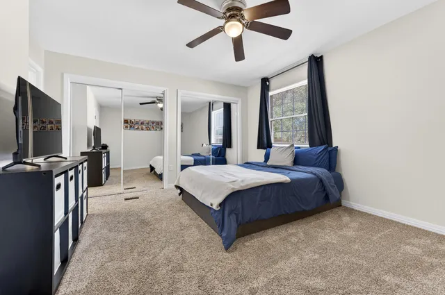 a spacious bedroom with a bed and a flat tv screen on dresser