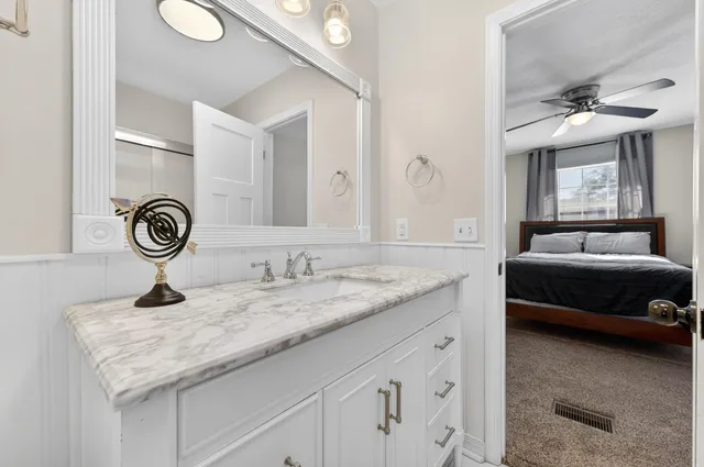 a en suite bathroom with a granite countertop sink and a mirror