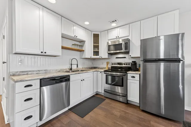 a kitchen with cabinets stainless steel appliances a sink and wooden floor