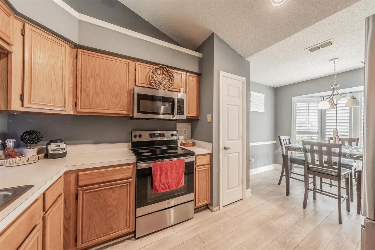 4520 Wedgecrest Drive Dallas, TX 75232 - Photo 7 of 19 a kitchen with stainless steel appliances granite countertop a stove a sink dishwasher a microwave oven and white cabinets with wooden floor