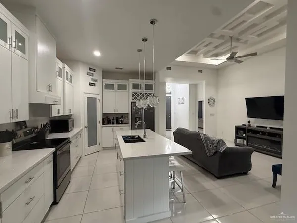 a living room with stainless steel appliances furniture a flat screen tv and kitchen view
