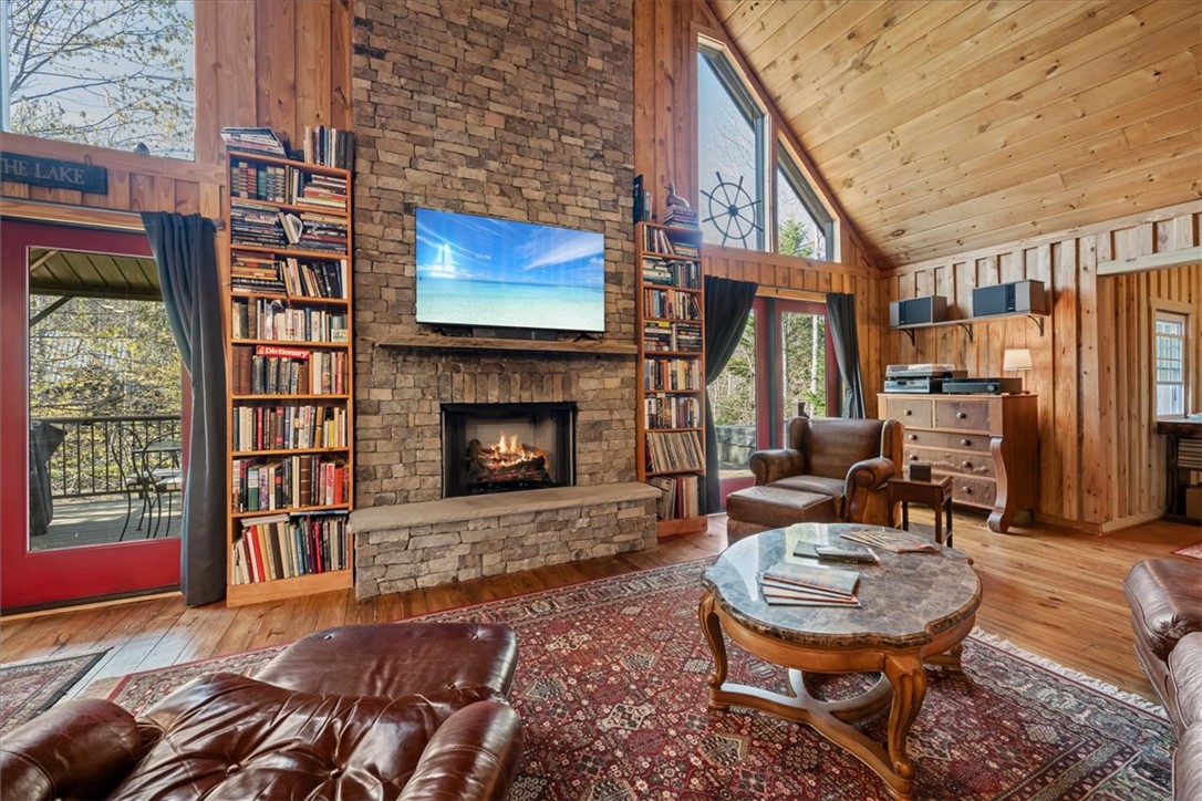 109 Carolina Cove Road Seneca, SC 29672 - Photo 8 of 45 This inviting living space features a warm stone fireplace, rich wood paneling, and an expansive window.