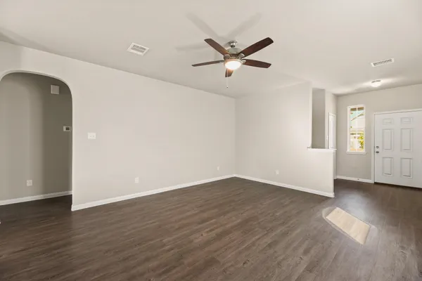 an empty room with wooden floor closet and windows