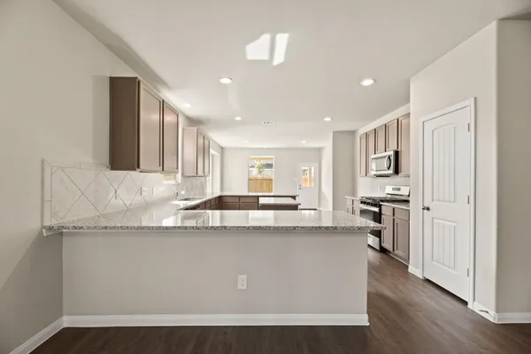 a large kitchen with stainless steel appliances granite countertop a lot of counter space and wooden floors