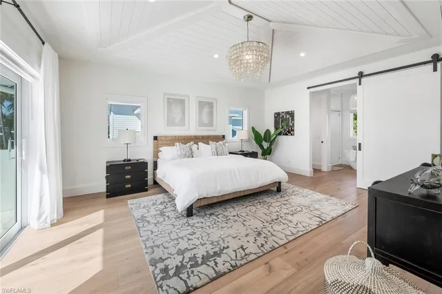 a spacious bedroom with a bed and a flat screen tv