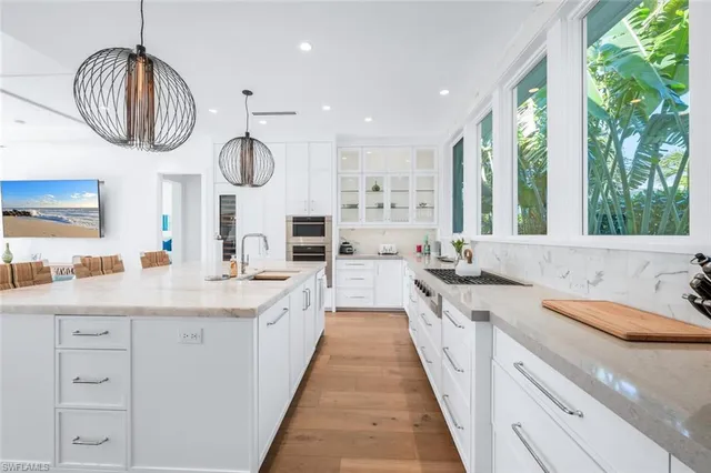 a large kitchen with a large counter space a sink stainless steel appliances and cabinets