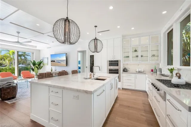 a kitchen with stainless steel appliances kitchen island granite countertop a stove a sink and a chandelier