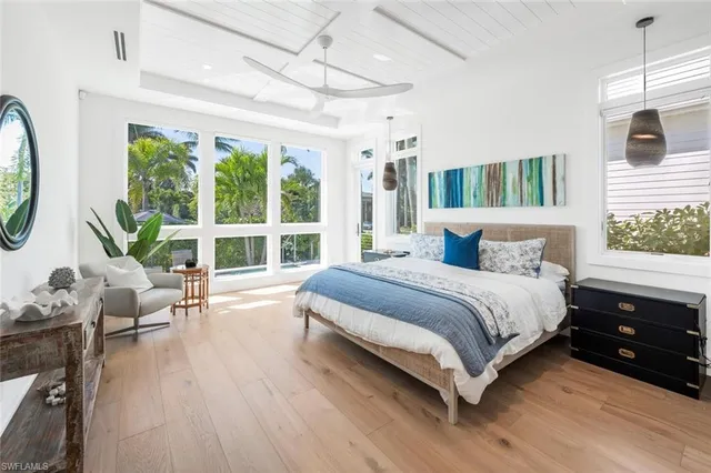 a bedroom with a bed a mirror on dresser and a large window
