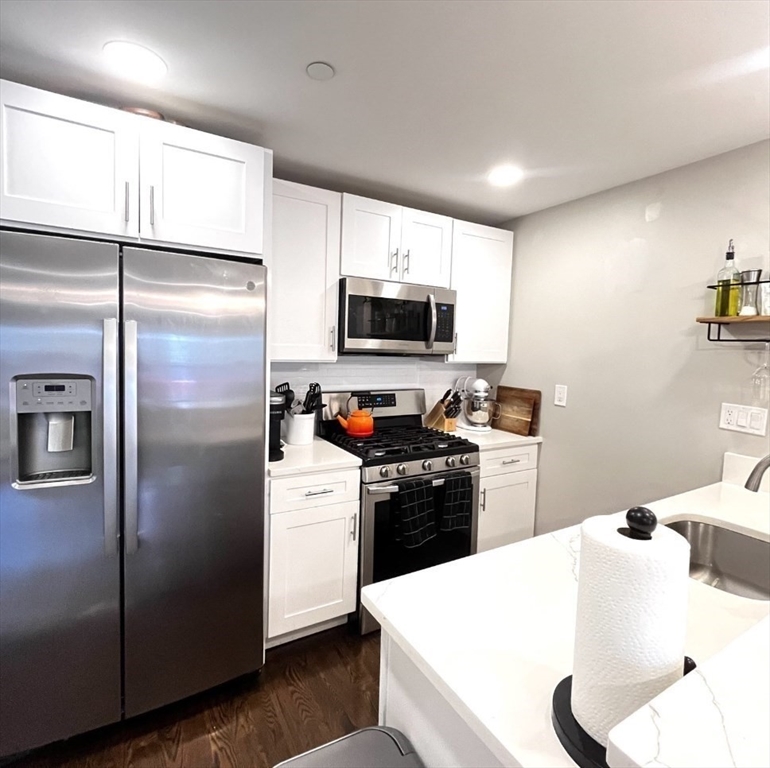 229 Maverick Street, Unit 1 Boston, MA 02128 - Photo 7 of 20 a kitchen with a refrigerator a stove top oven a sink and cabinets