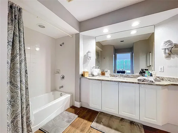 a bathroom with a granite countertop sink mirror and bathtub