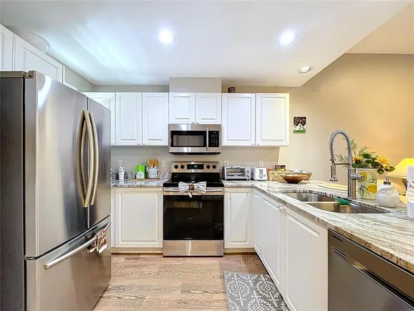 a kitchen with stainless steel appliances a dining table chairs and wooden floor