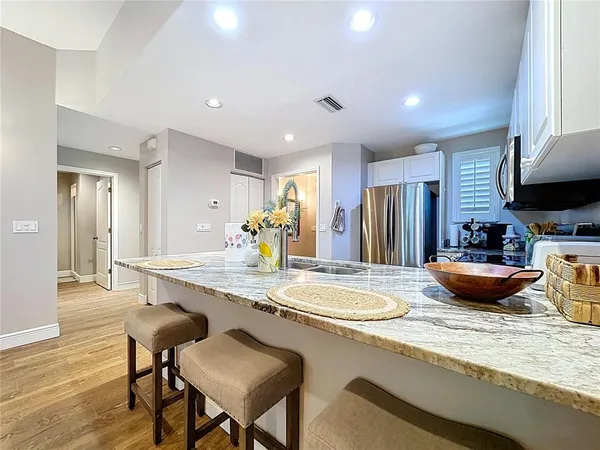 a kitchen with stainless steel appliances granite countertop a table chairs sink and cabinets