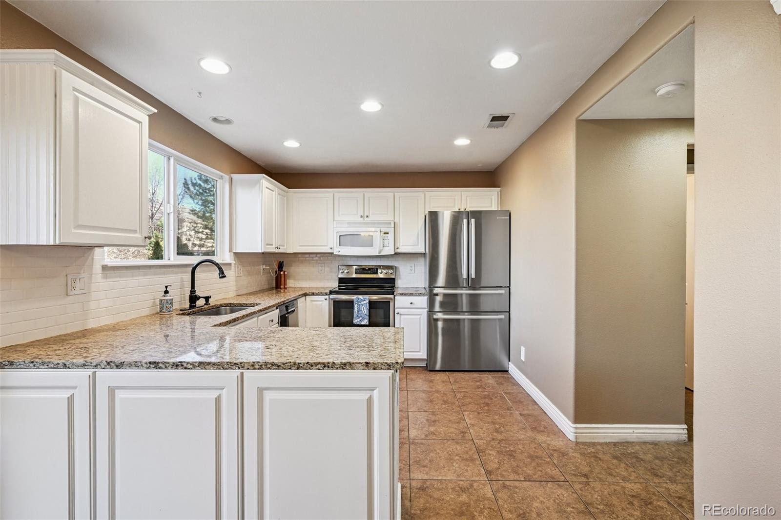 1135 Riddlewood Lane Highlands Ranch, CO 80129 - Photo 5 of 23 a kitchen with stainless steel appliances granite countertop a refrigerator sink and stove