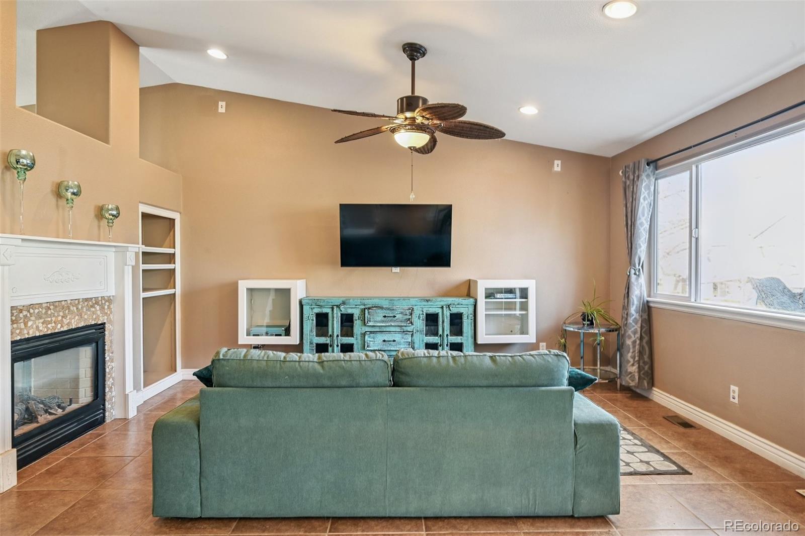 1135 Riddlewood Lane Highlands Ranch, CO 80129 - Photo 7 of 23 a living room with furniture a fireplace and a flat screen tv