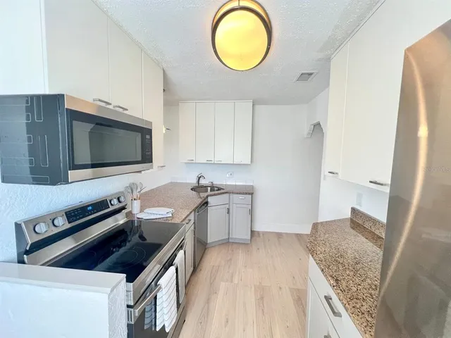 a kitchen with granite countertop a sink a stove and cabinets
