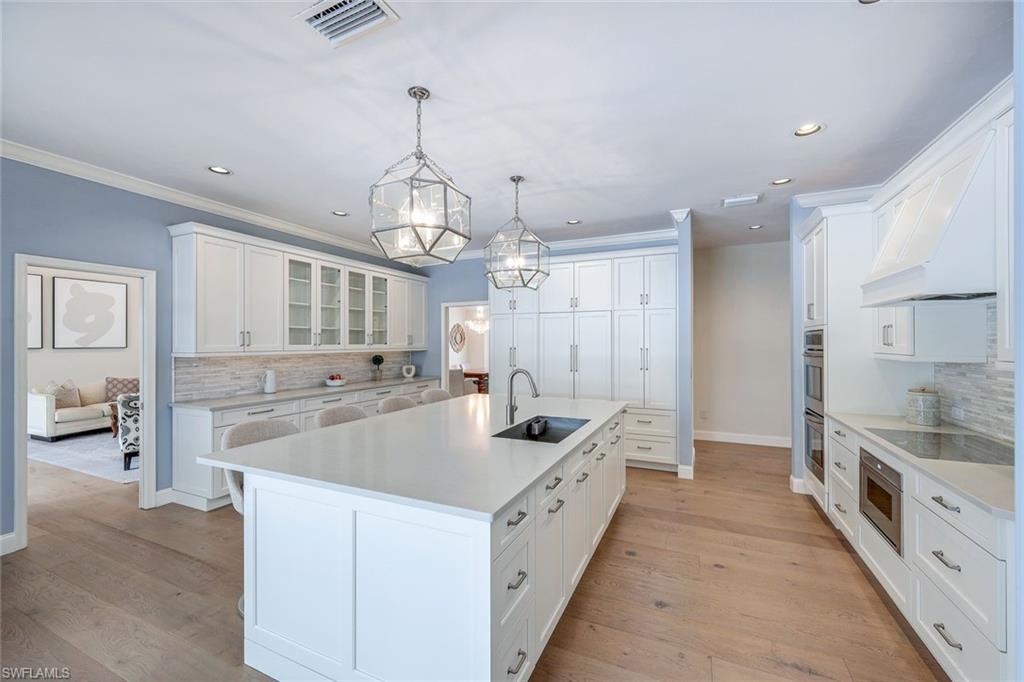a large white kitchen with a large counter top sink and refrigerator