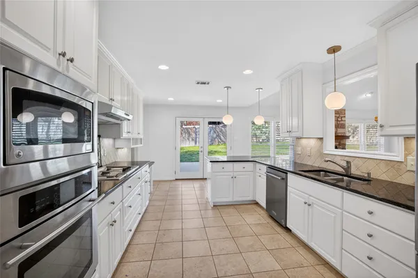 a large kitchen with stainless steel appliances kitchen island granite countertop a stove a sink and a microwave