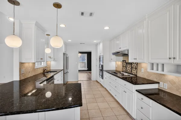 a kitchen with stainless steel appliances granite countertop a sink a stove and cabinets