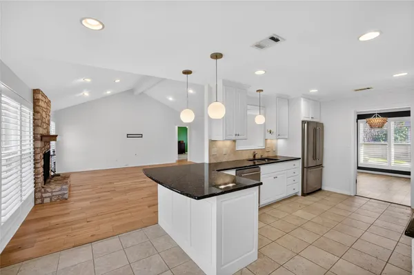 a kitchen with stainless steel appliances kitchen island granite countertop a stove a sink and a refrigerator