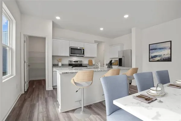 a kitchen with stainless steel appliances granite countertop a refrigerator a stove top oven a sink dishwasher and white cabinets with wooden floor