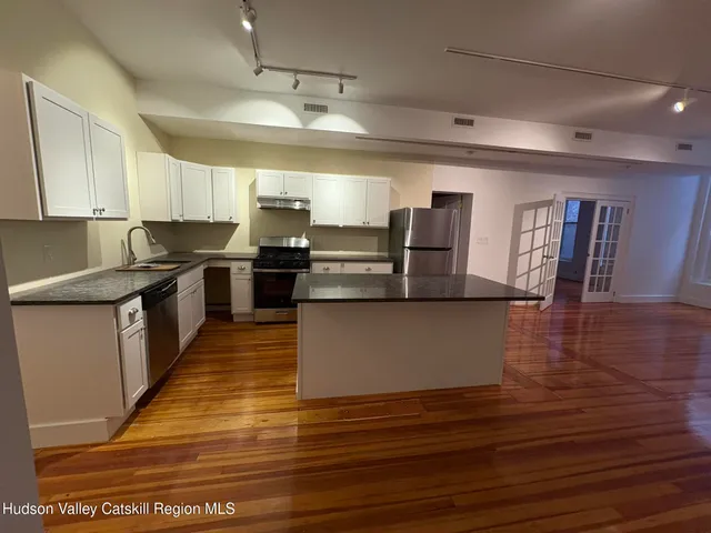 a large kitchen with stainless steel appliances granite countertop a large counter top a stove and a refrigerator