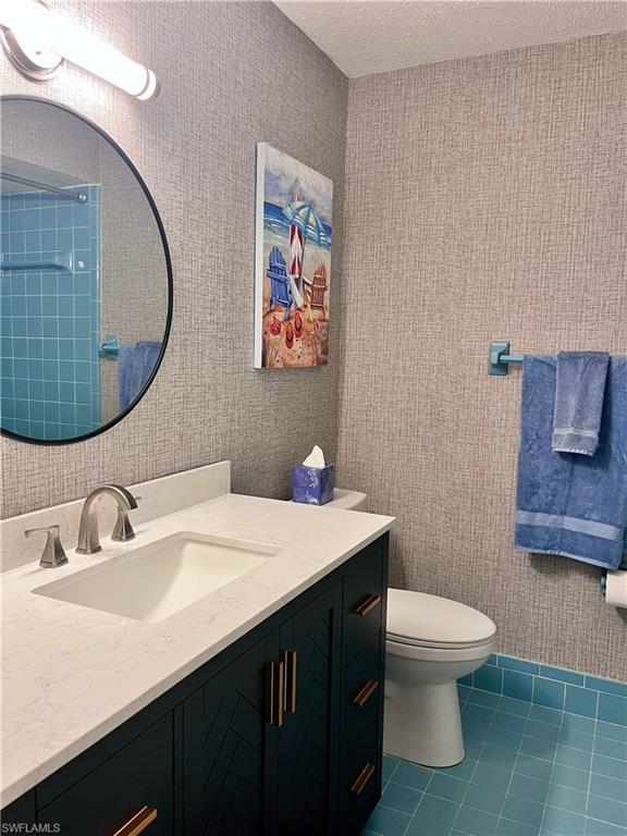 186 Harrison Road, Unit H4 Naples, FL 34112 - Photo 13 of 34 Full bath featuring dark tile patterned flooring, vanity, wallpapered walls, and a textured ceiling