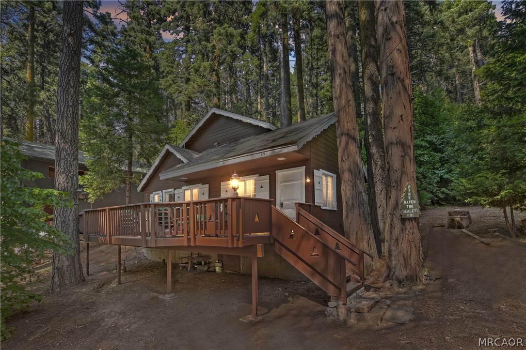 691 Cottage Grove Road Lake Arrowhead, CA 92352 - Photo 1 of 28 a wooden bench sitting in the middle of a forest