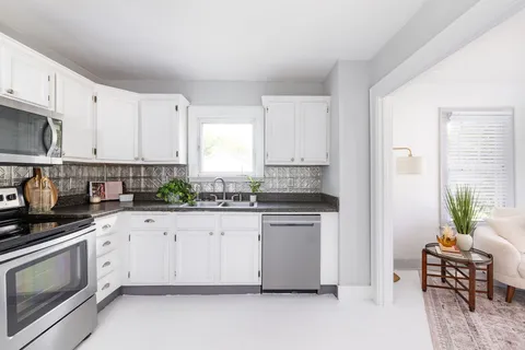 a kitchen with granite countertop white cabinets and white appliances