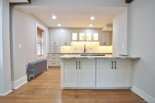 a kitchen with kitchen island granite countertop white cabinets and window