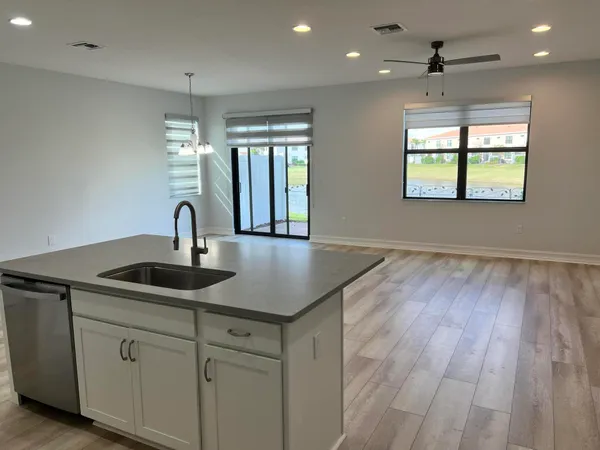 a kitchen with stainless steel appliances granite countertop a sink a window and wooden floor