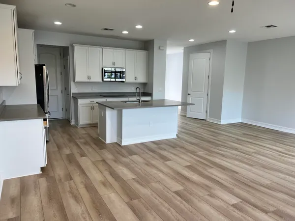 a kitchen with stainless steel appliances granite countertop a sink a stove top oven a refrigerator and white cabinets