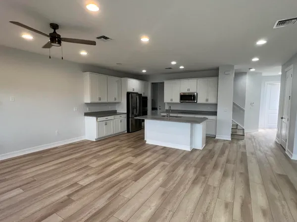 a large kitchen with kitchen island a stove a refrigerator cabinets and wooden floor