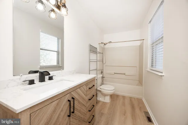 a bathroom with a sink a toilet a mirror and shower