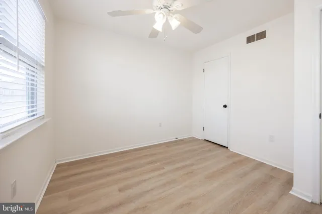 an empty room with a window and a fan